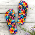 Colorful Hawaiian Style floral pattern flip-flops on a wooden surface with flowers in the background