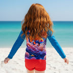 A long-sleeve raglan rash guard shirt featuring a vibrant underwater graphic print of a clownfish swimming among colorful coral reefs, worn by a little redhead girl on Fort Myers Beach
