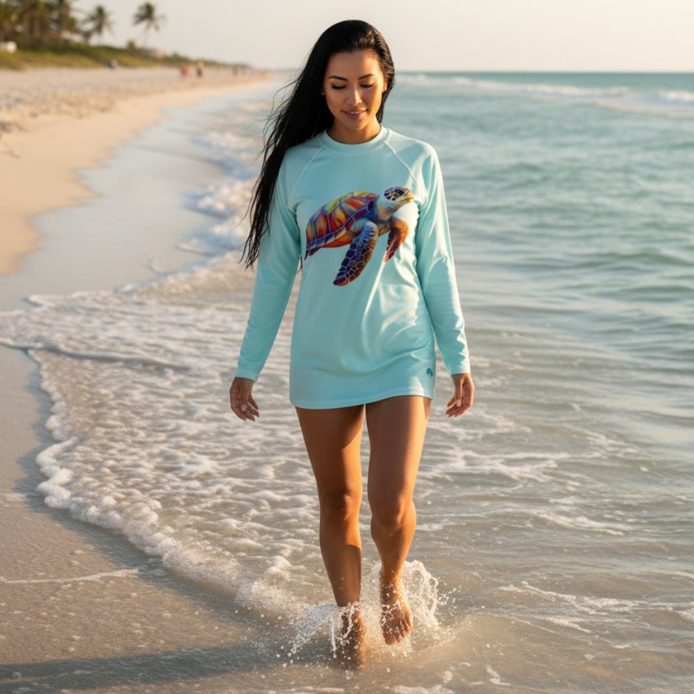 Light blue long-sleeve sun rashie with a colorful turtle design on swimsuit model walking through the waves in Fort Myers Beach