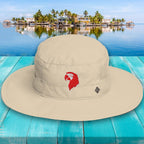 Beige bucket hat with a red logo on a blue wooden surface with a scenic background