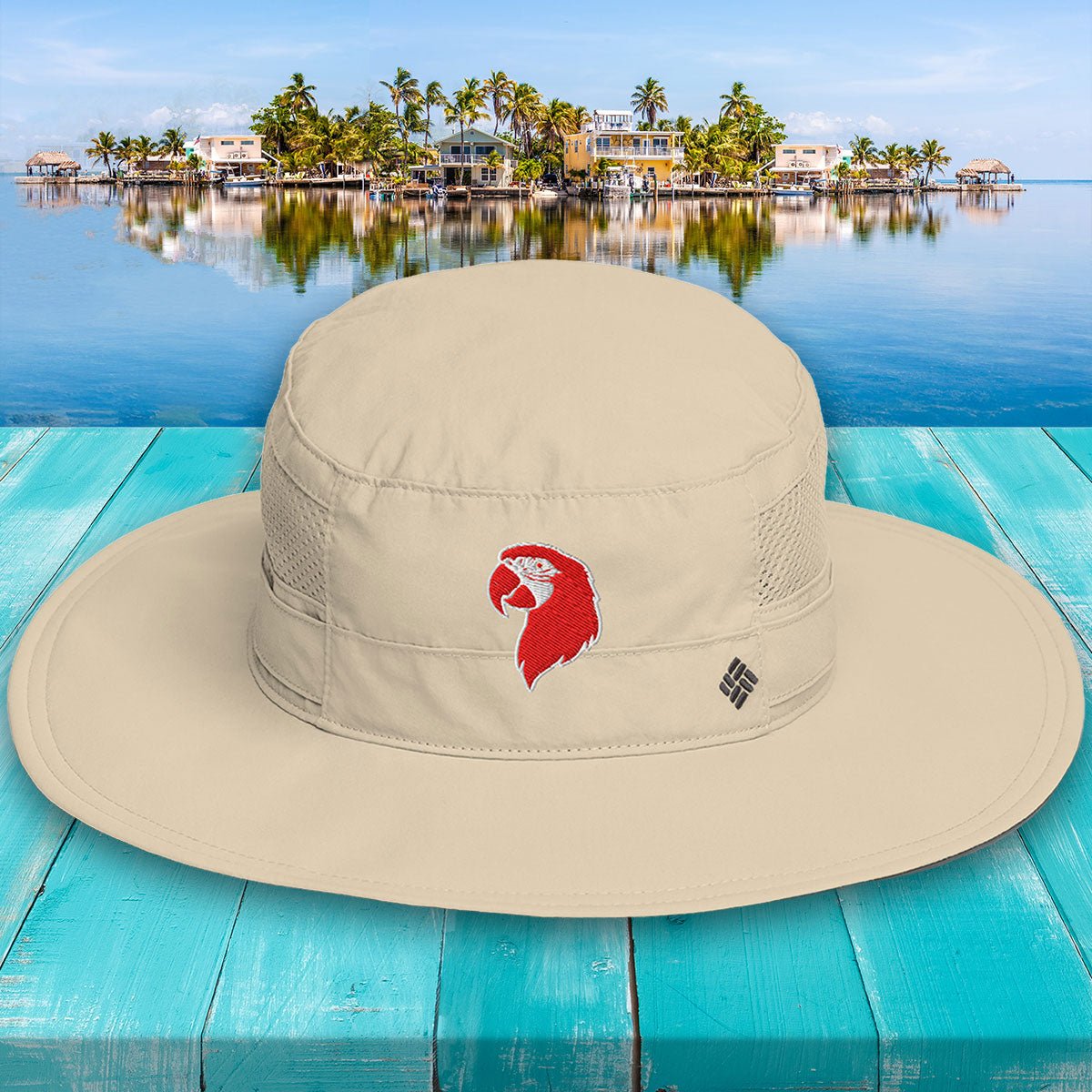 Beige bucket hat with a red logo on a blue wooden surface with a scenic background