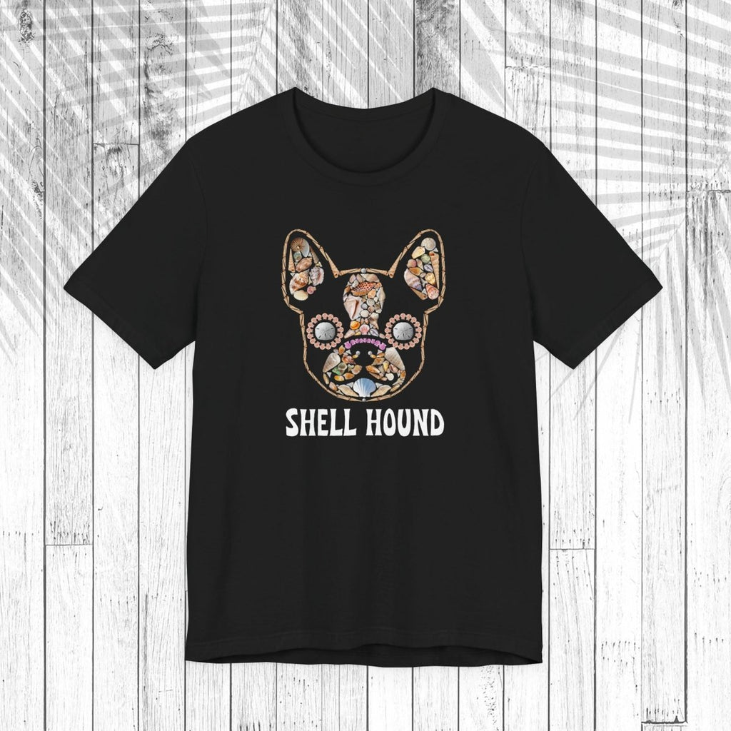 A black short-sleeve t-shirt with a graphic of a French Bulldog decorated with a colorful floral pattern and the text 'SHELL HOUND' printed below in white, displayed on a white wood plank background.