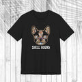 A black short-sleeve t-shirt with a graphic of a French Bulldog decorated with a colorful floral pattern and the text 'SHELL HOUND' printed below in white, displayed on a white wood plank background.
