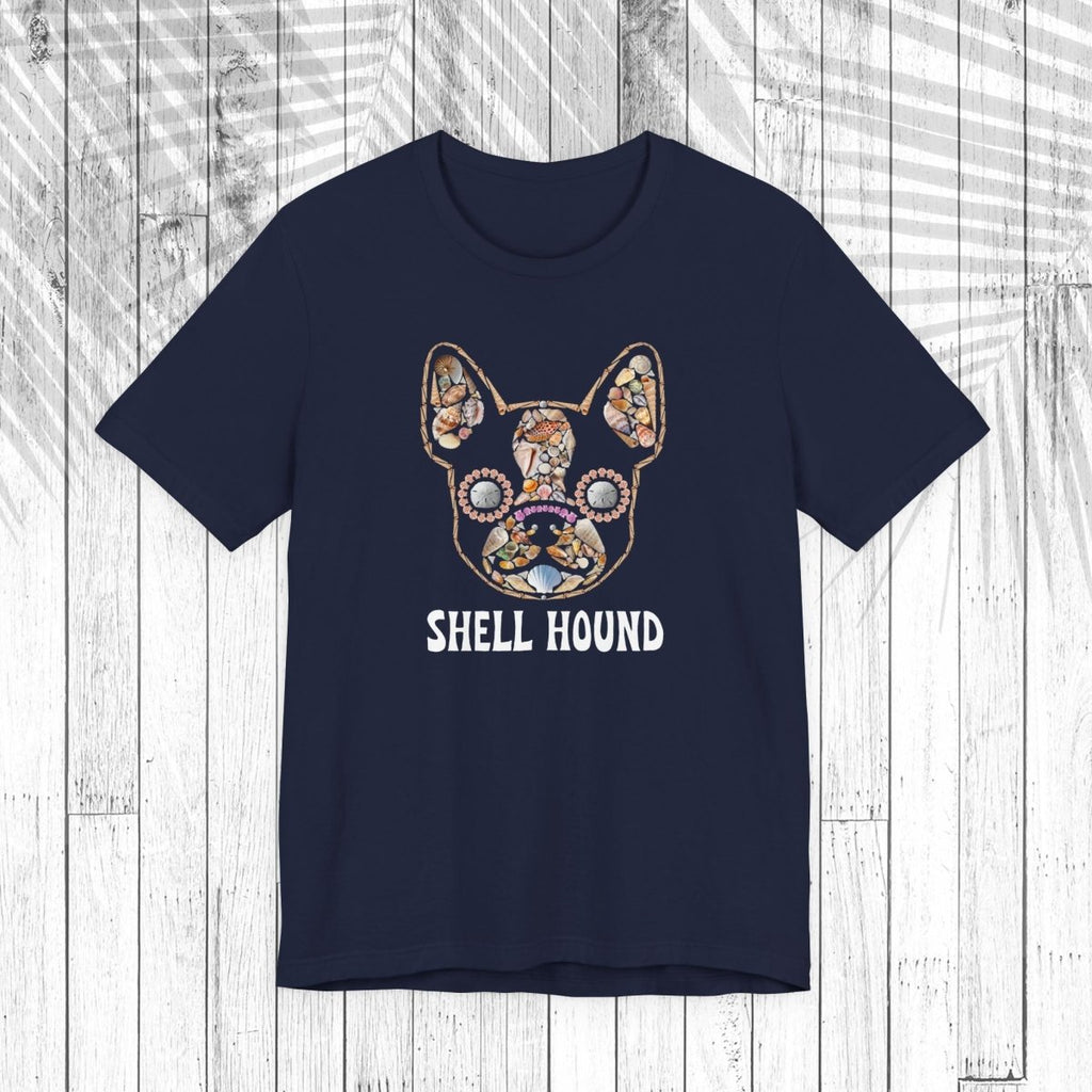A dark navy short-sleeve t-shirt with a graphic of a French Bulldog decorated with a colorful seashell pattern and the text 'SHELL HOUND' printed below in white, displayed on a white wood plank background.