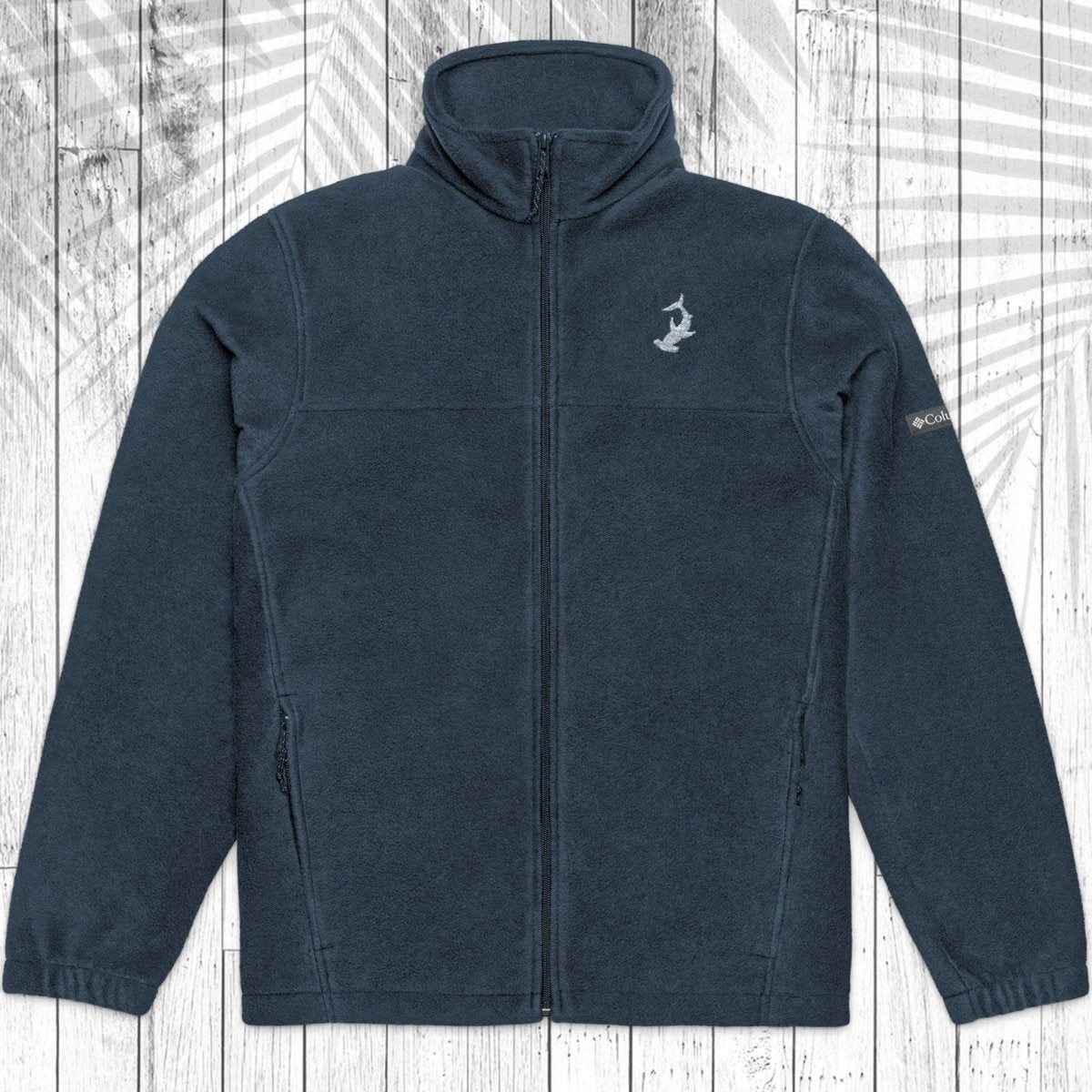 A black fleece zip-up jacket with a stand-up collar, laid flat against a white wood plank background with a faint palm leaf pattern.