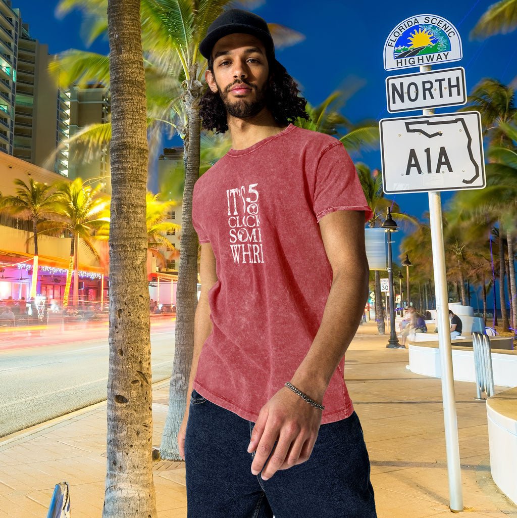 Man in a red t-shirt standing next to a 'Highway A1A' sign with palm trees and a cityscape in the background.