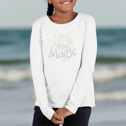 Child wearing a white long-sleeve shirt with 'Little Miss Magic' text on St. Pete Beach
