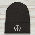 Black beanie with a white peace sign emblem on a rustic wood background