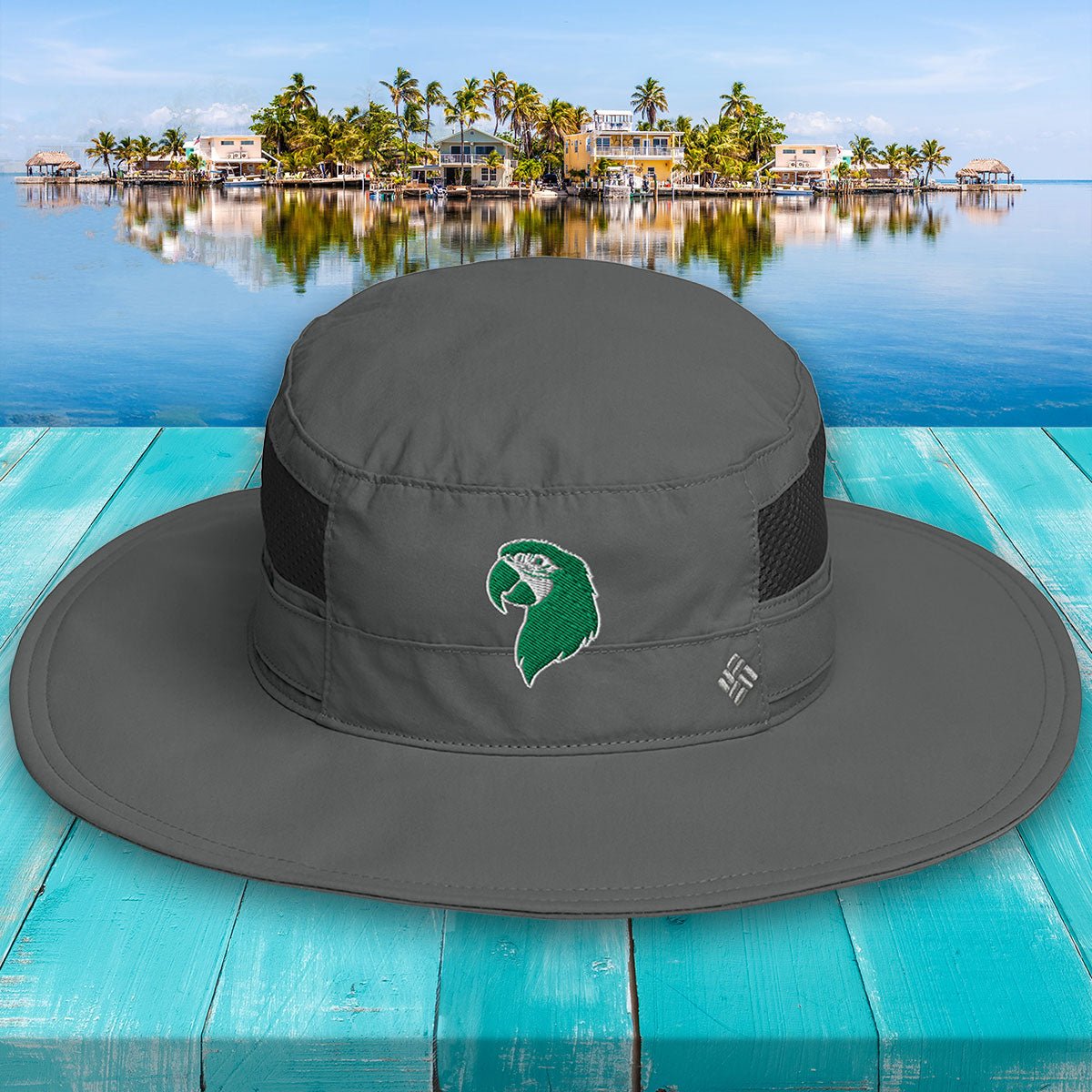 Gray wide-brimmed hat with a logo on a turquoise wooden surface with a scenic background.