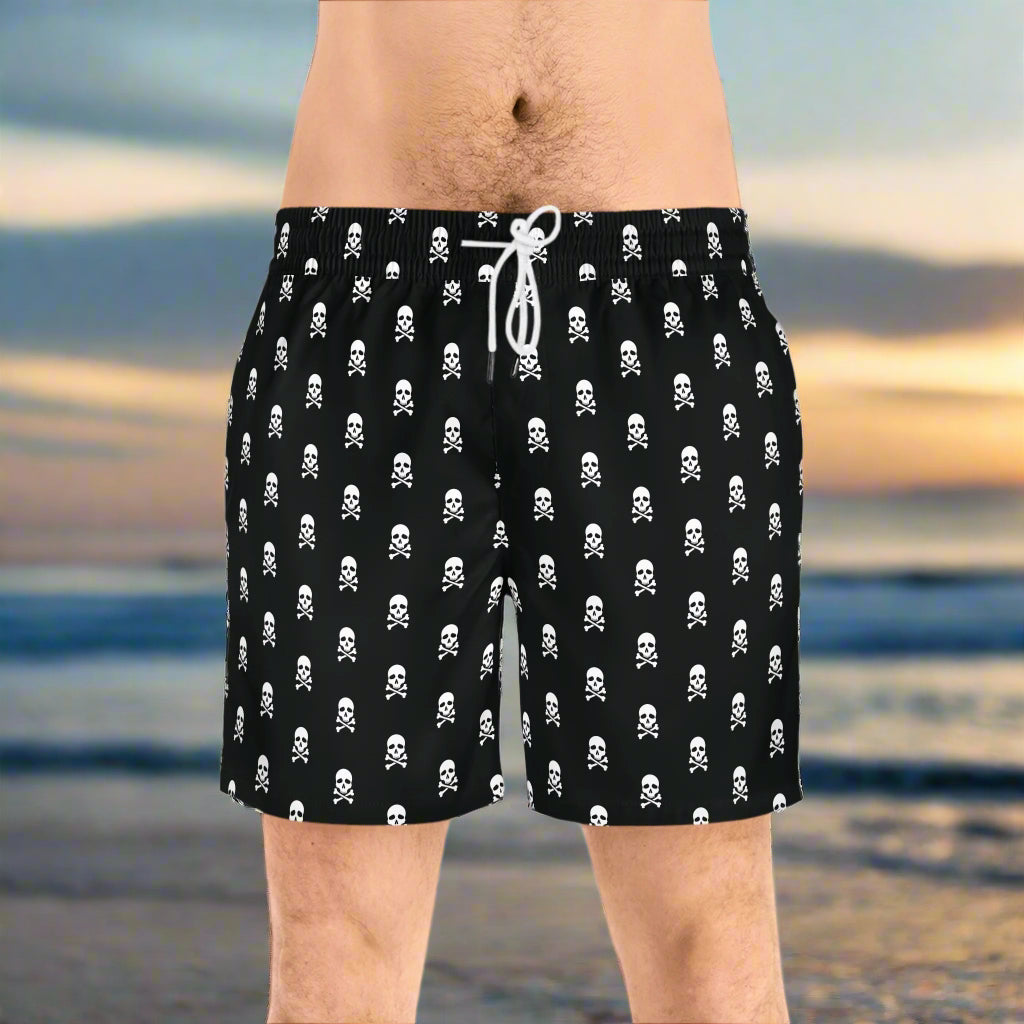 Guy wearing pirate pattern swim trunks standing on an island beach at sunset