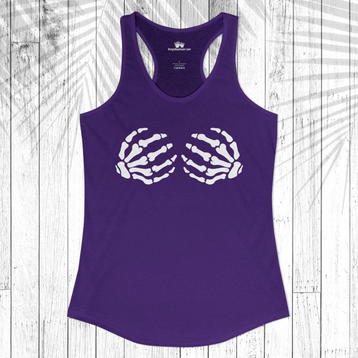 A purple racerback tank top with a white skeleton hand graphic on the chest, displayed flat against a white wood plank background with a palm leaf overlay.