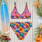 Colorful floral swimsuit on a wooden background with beach accessories.
