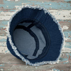 Blue denim bucket hat with frayed edges on a white background