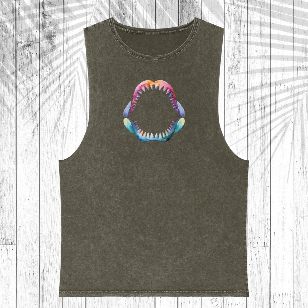 A sleeveless dark olive green muscle tank top featuring a colorful graphic of an open mouth with sharp teeth on the chest, displayed flat against a white wood plank background with a palm leaf overlay.