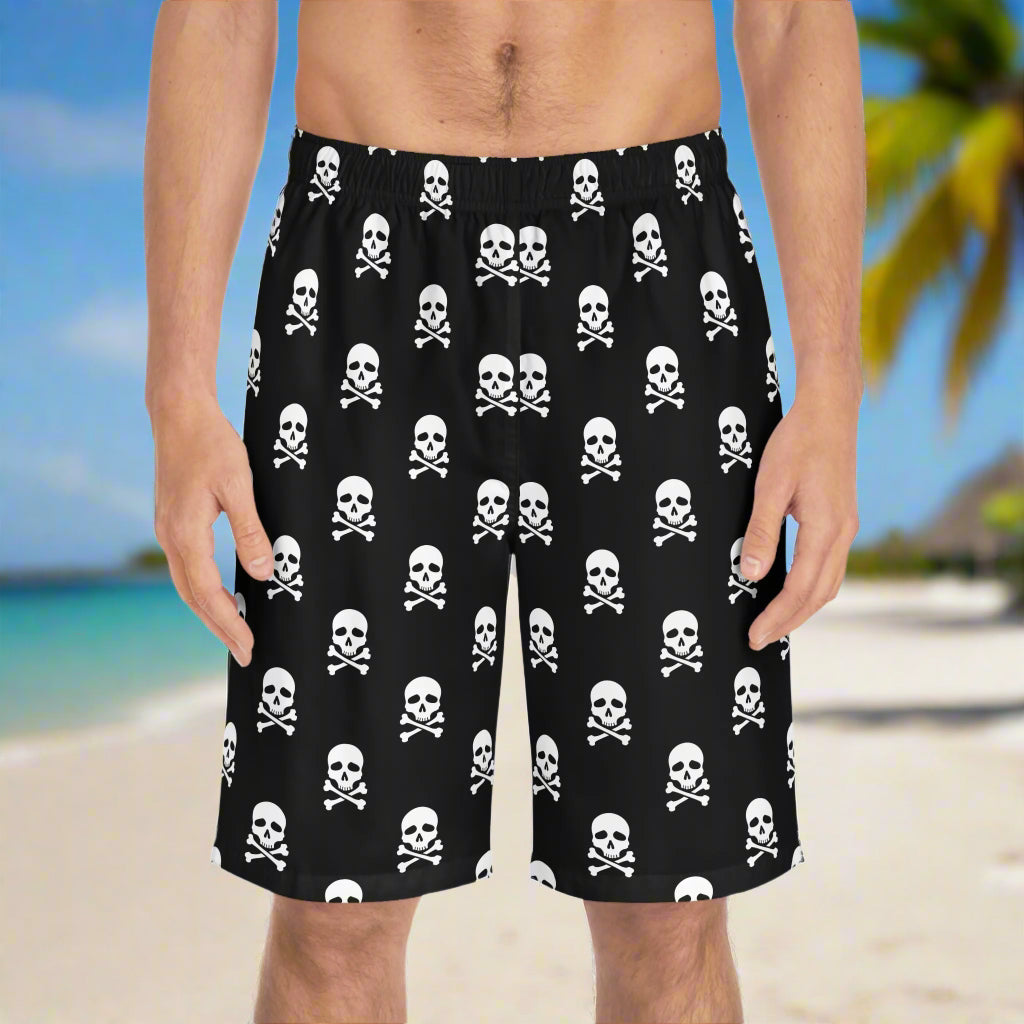 Men's Board Shorts with skull and crossbones in a polka-dot pattern worn by a surfer dude standing on and island beach