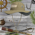 Beige bucket hat with embroidered jolly roger pirate skull emblem on a wooden background with nautical items.