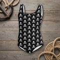 Black swimsuit with white skull and crossbones pattern on a rustic wood nautical background