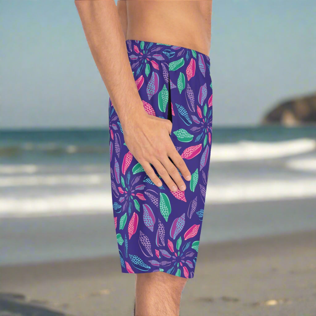 Guy wearing junonia board shorts standing on a beach with his thumb in his pocket