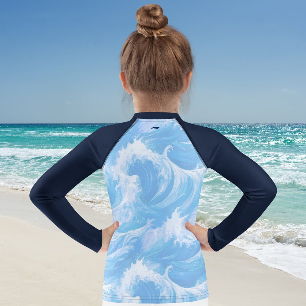 girl wearing a long sleeve rashie with ocean wave design on a beach
