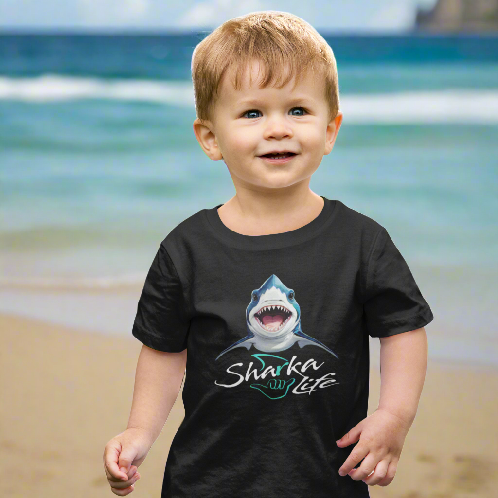 Child wearing a black t-shirt with a shark graphic and sharka life text standing on the beach in Waikiki 
