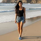 beautiful woman wearing tie dye beach slippers with blue jean shorts and a black tank top walking on Half Moon Bay State Beach in California