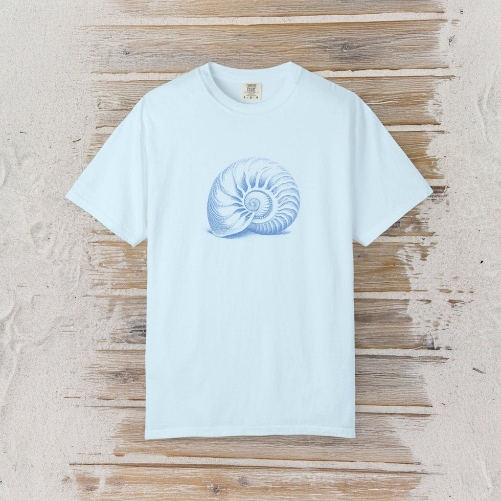A light blue short-sleeve crewneck t-shirt featuring a blue nautilus shell graphic on the chest, laid flat on a rustic wooden plank background.