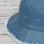 Close-up of a blue denim bucket hat with frayed edge on a rustic wood background