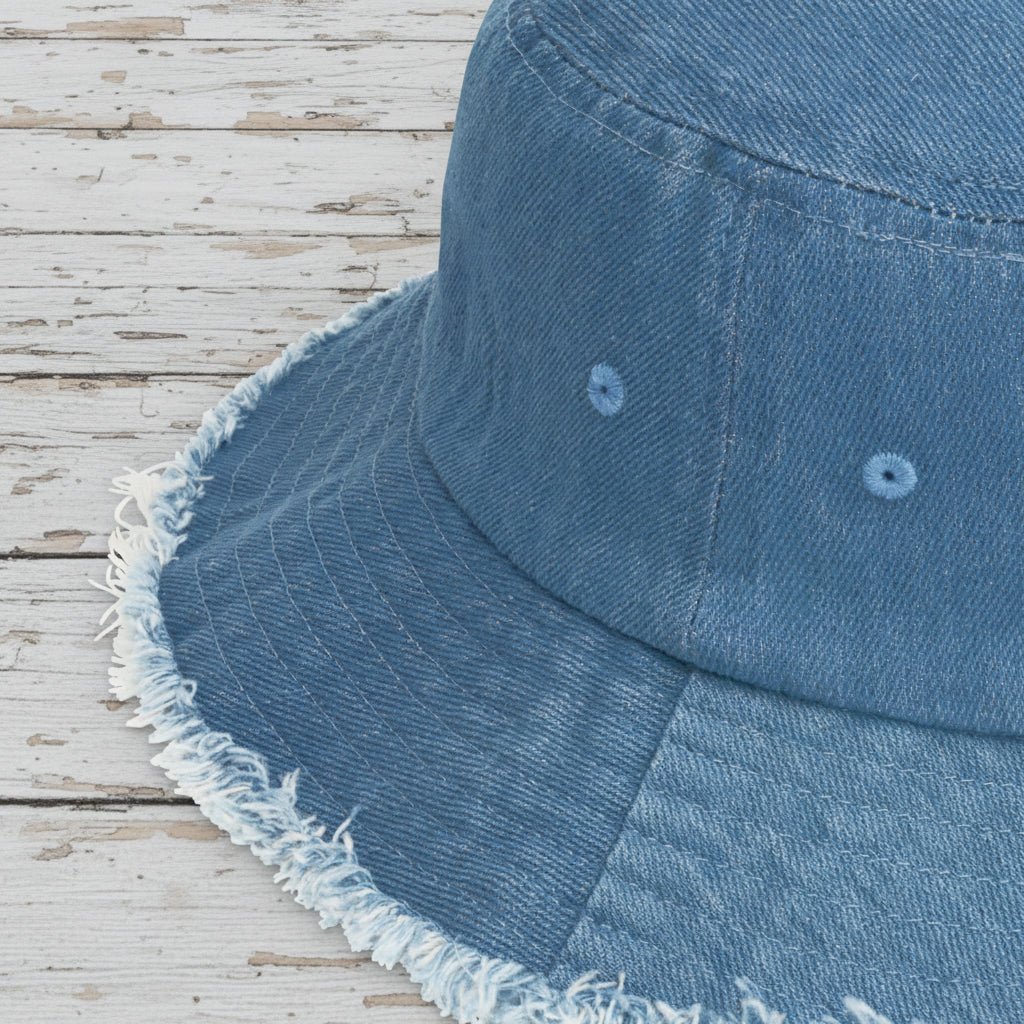 Close-up of a blue denim bucket hat with frayed edge on a rustic wood background