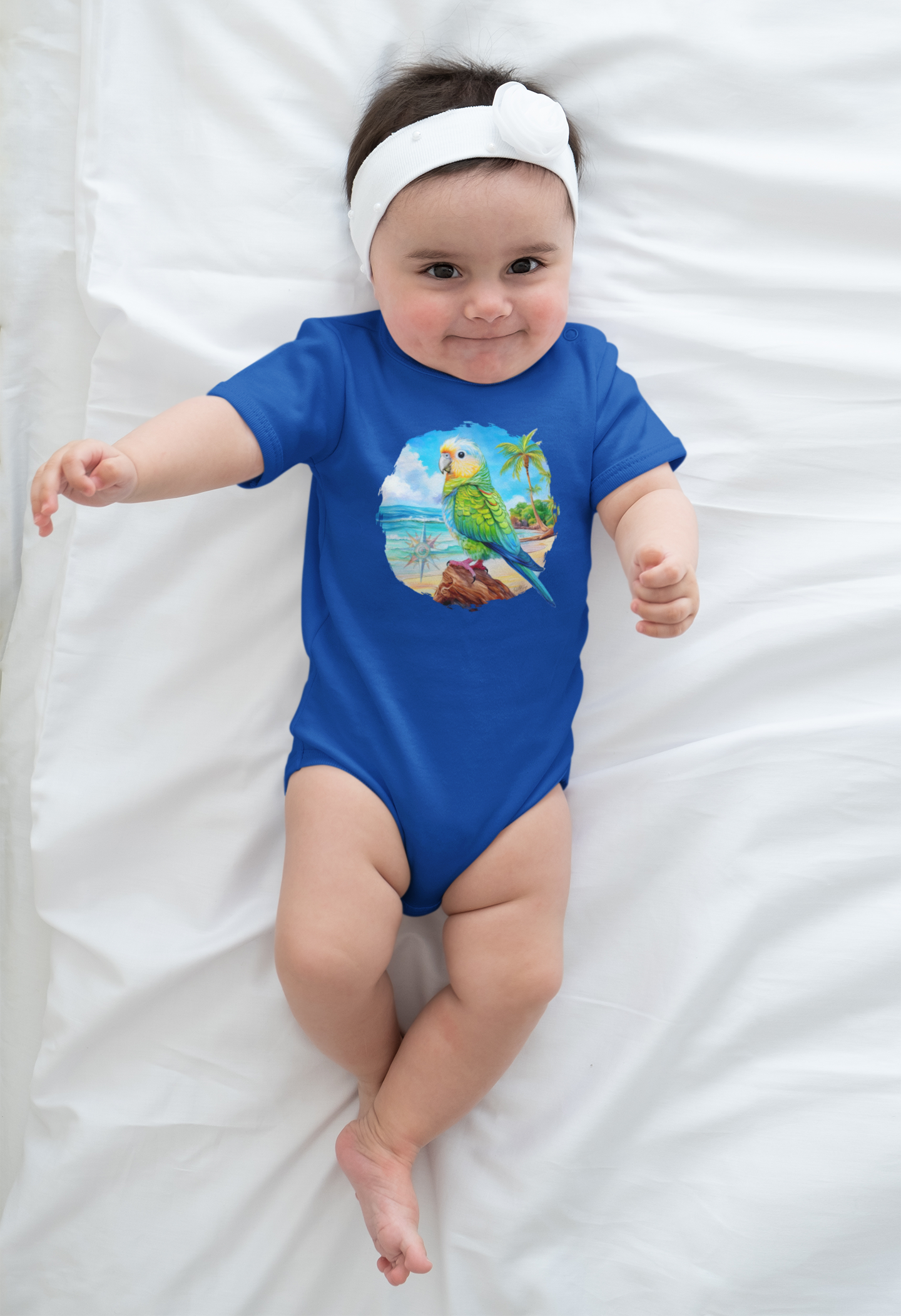 Baby wearing a blue onesie with a parrot head design on a white blanket