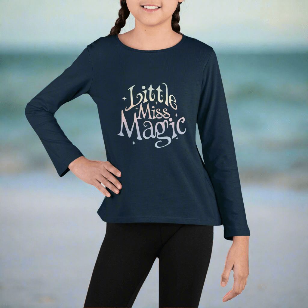 Child wearing a navy blue long-sleeve shirt with 'Little Miss Magic' text on  St. Pete Beach