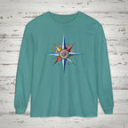 Teal long-sleeve shirt with a colorful compass design on a wooden background