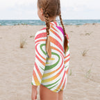 Girl wearing a colorful striped long sleeve one piece on Anna Maria Island Beach.