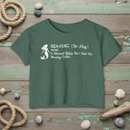 Green t-shirt with mermaid graphic and text on a rustic nautical background