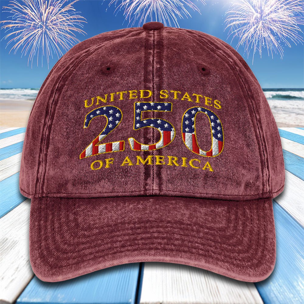 Maroon cap with 'United States 250 of America' text and American flag design on a beach with fireworks background.