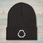 Black beanie with a white megalodon jaw embroidery on a faded wood background