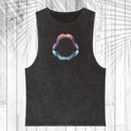 A black washed sleeveless tank top featuring a colorful graphic of an open shark mouth on the chest, displayed flat against a white wood plank background with a palm leaf overlay.