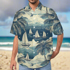 Man wearing a button up Hawaiian shirt with a teal toned graphic tropical design featuring palm trees and sailboats, standing on a beach in Hawaii