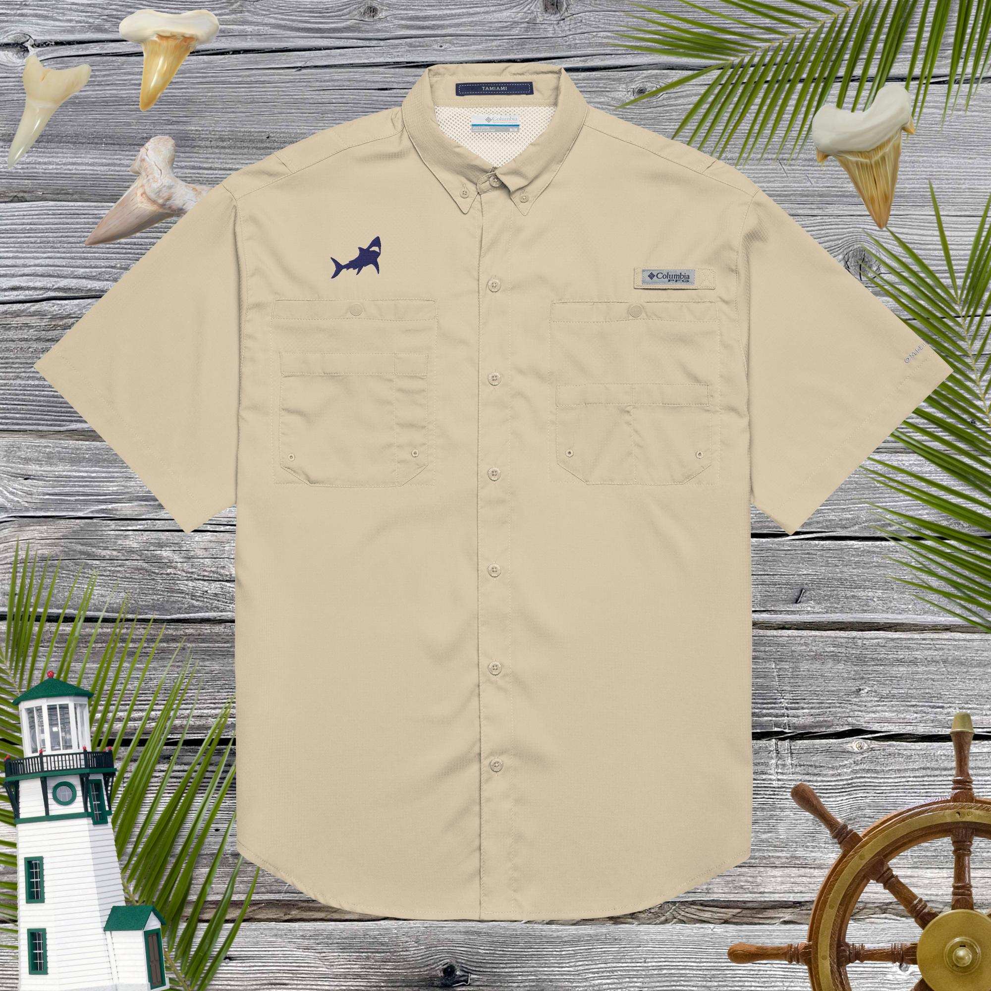 Beige short-sleeve shirt with shark embroidery over a wooden background with decorative sea elements.