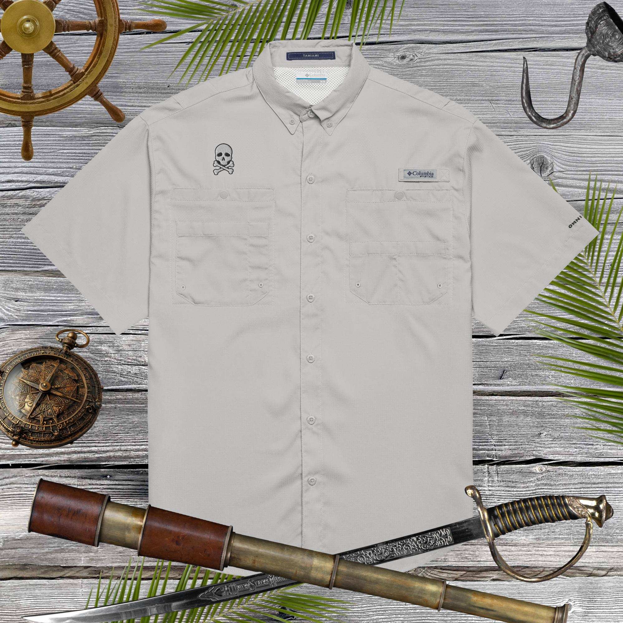 Beige short-sleeve shirt with embroidered skull design on a wooden background with nautical elements.