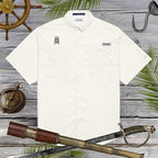 White shirt with embroidered skull design on a wooden background with nautical items