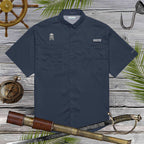 Navy blue fishing shirt with pirate skull embroidery on a wooden surface with nautical-themed props.