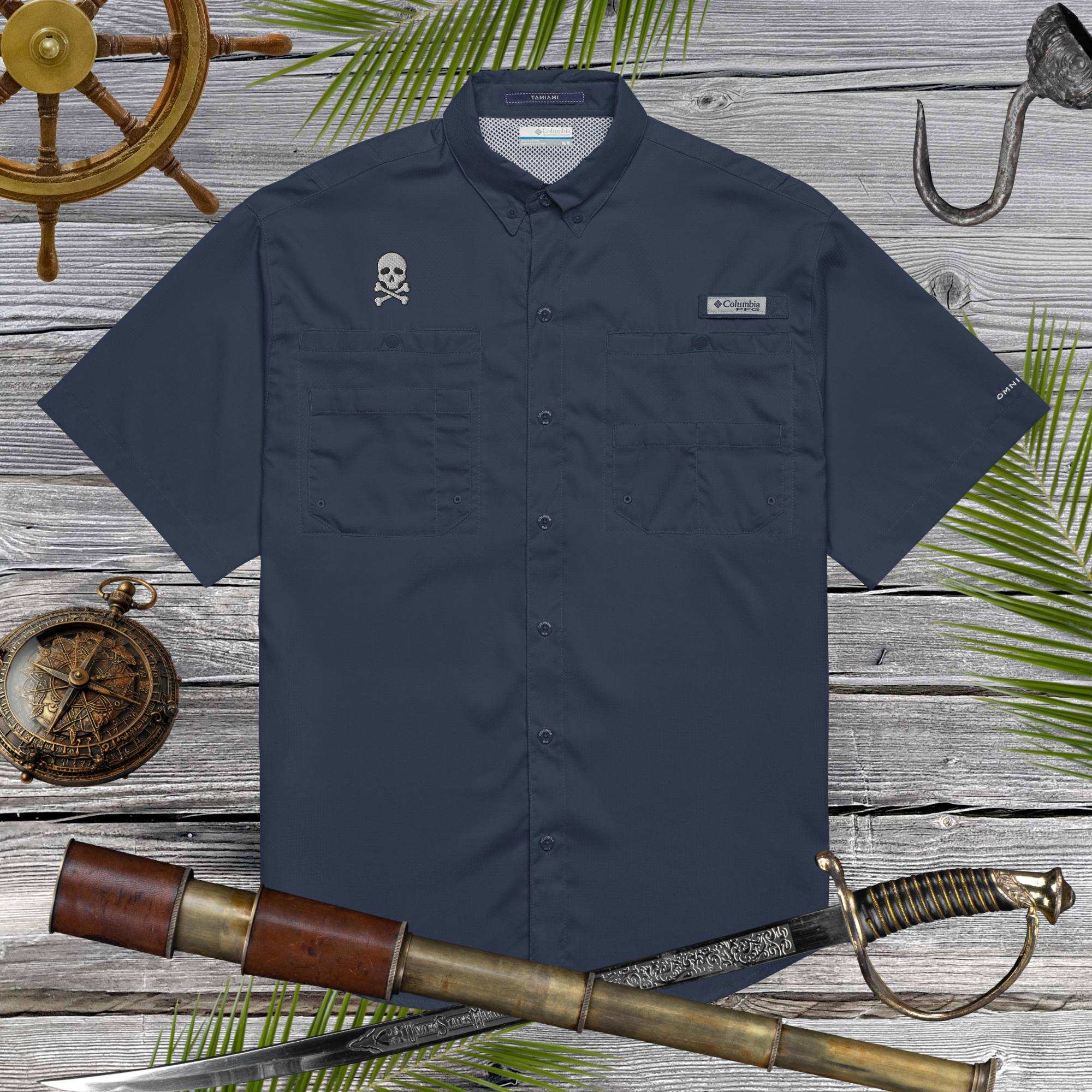 Navy blue fishing shirt with pirate skull embroidery on a wooden surface with nautical-themed props.