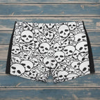Person wearing black and white skull patterned swim shorts on a beach.