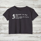 Navy blue t-shirt with white mermaid graphic and text on a rustic wood background