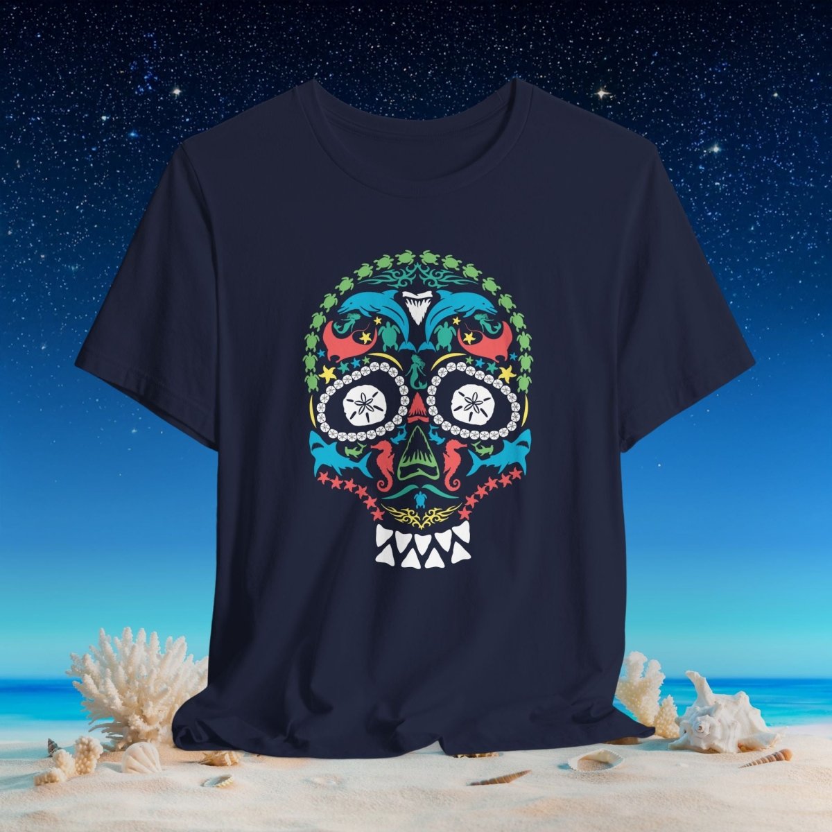 A navy blue short-sleeve t-shirt featuring a colorful sealife sugar skull graphic, displayed against a beach and starry night sky background.