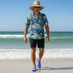 Dude wearing blue water shoes and black board shorts and a Hawaiian shirt walking on miramar beach in Destin Florida