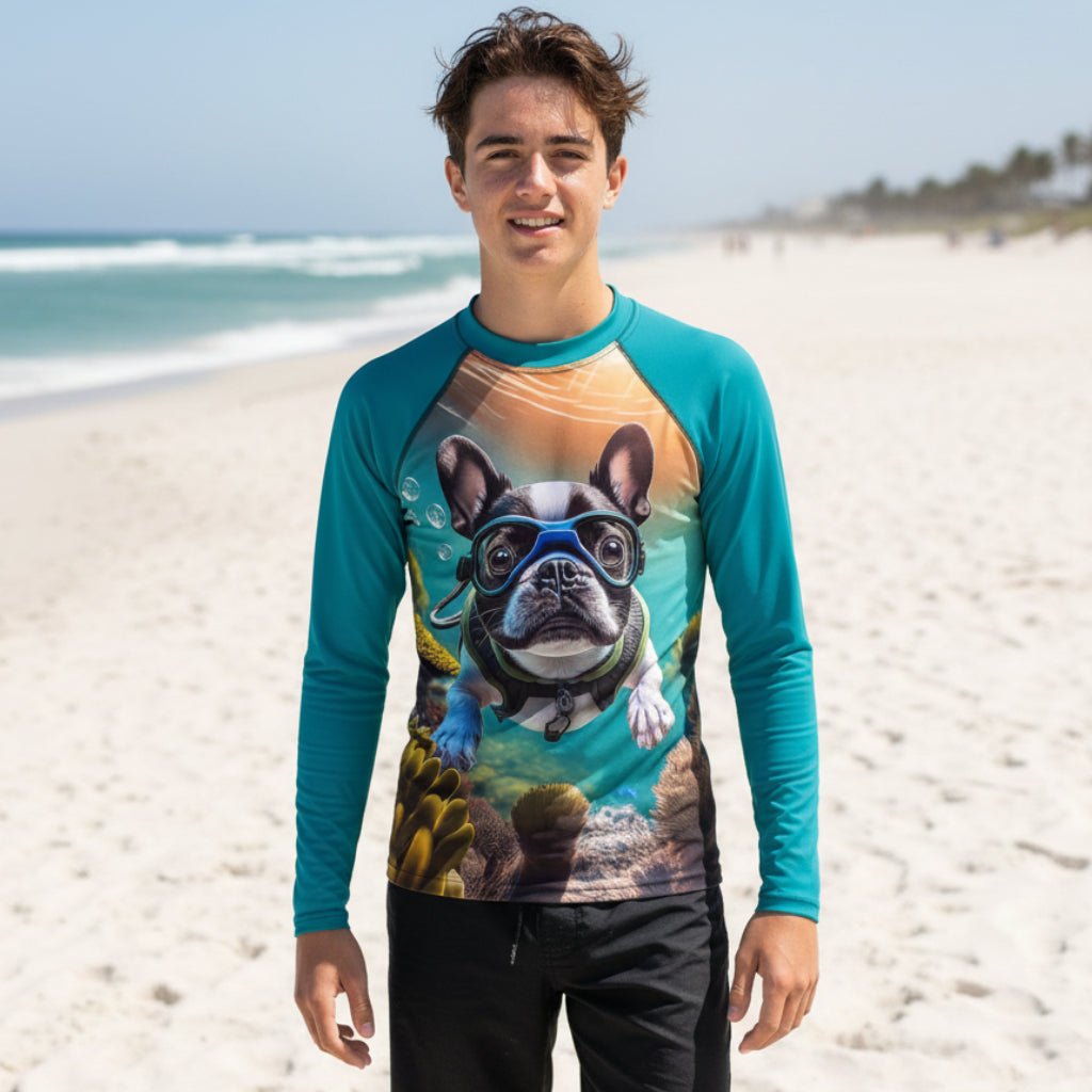 Teen dude wearing a long-sleeve raglan Sun Rashie with teal sleeves and a large graphic print of a French bulldog wearing a scuba diving mask on an underwater coral reef.