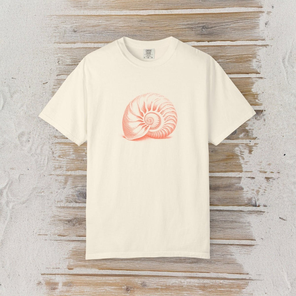 An off-white short-sleeve crewneck t-shirt featuring a pinkish-orange nautilus shell graphic on the chest, displayed flat against a rustic whitewashed wood background.