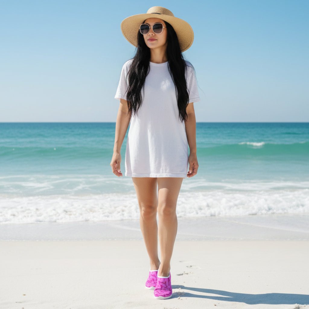Beautiful woman with long flowing black hair wearing pink shark slippers, sunglasses and a sunhat, walking on New Smyrna Beach