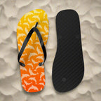 Flip-flop with dolphin pattern on a yellow and orange background, showing sole texture on a white beach background.